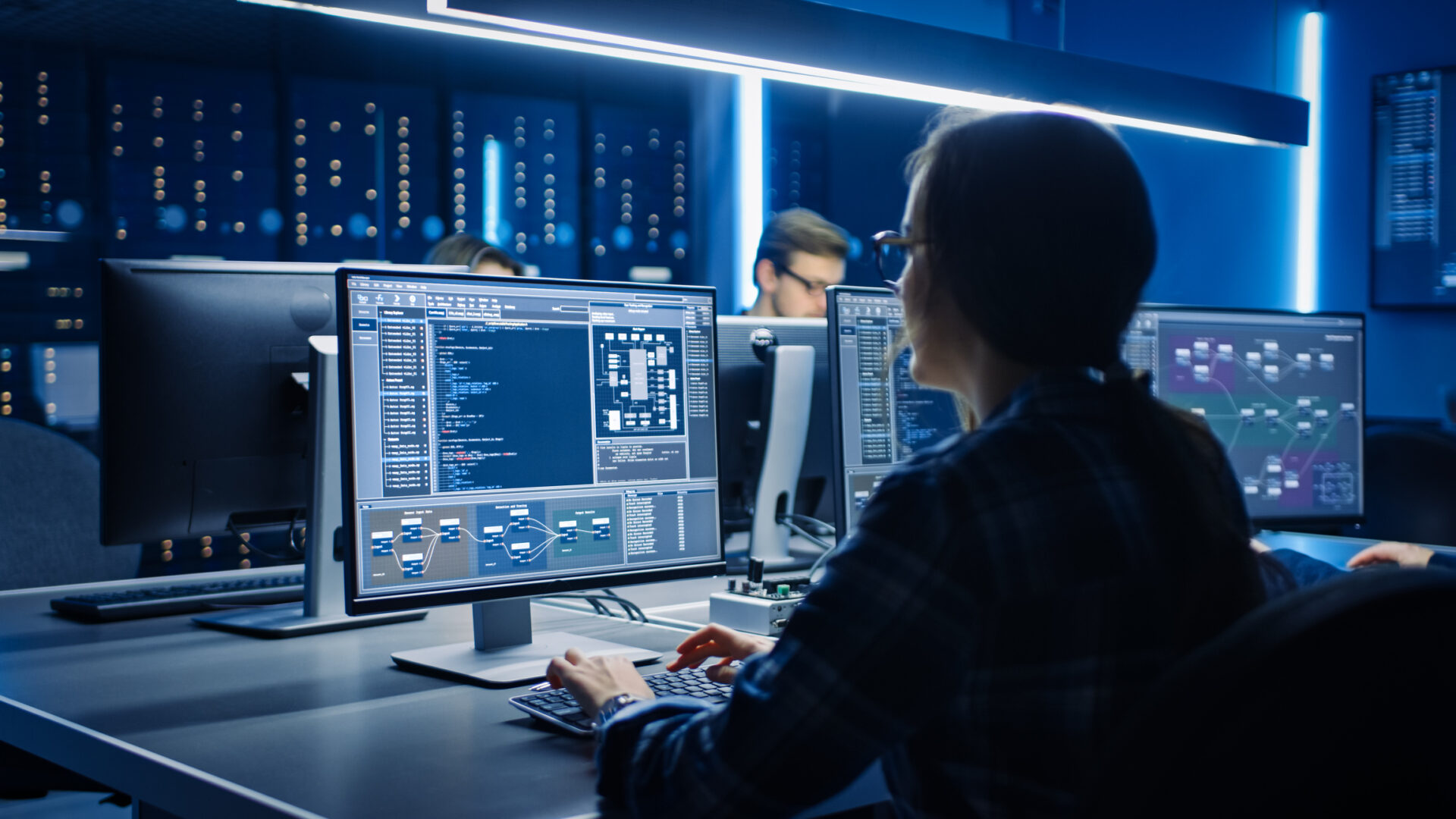 smart-female-it-programer-working-on-desktop-computer-in-data-center-system-control-room-team-of-young-professionals-doing-code-programming
